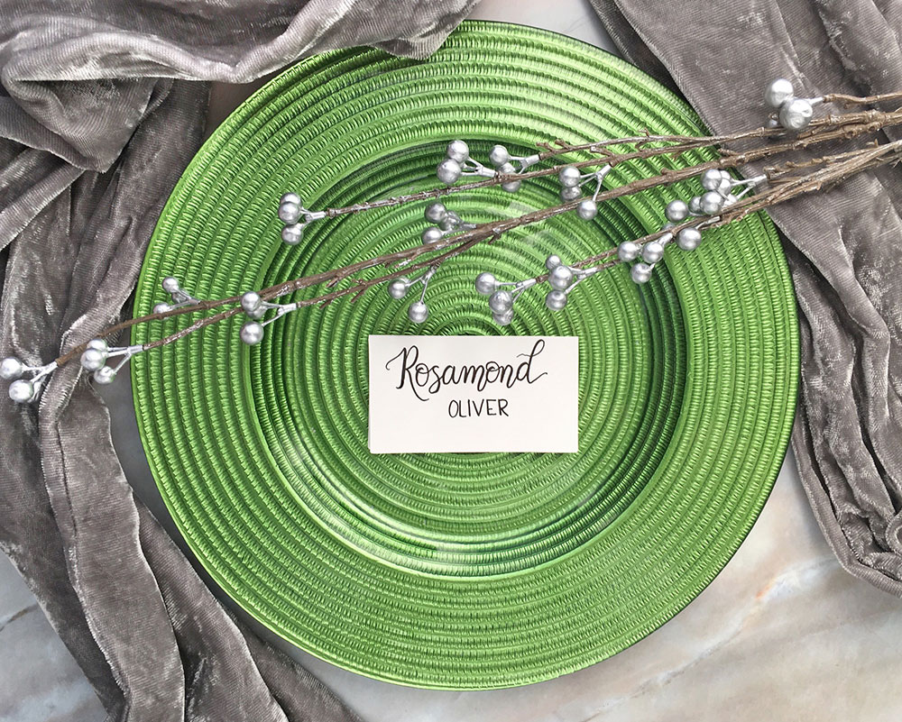 Hand Lettered Place Card Calligraphy Escort Card on a Green Wedding Place Setting with Scarf Prop and Marble Background